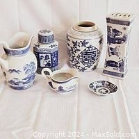 Collection of six blue and white porcelain items including vases, cruet, dish, and container on white cloth background