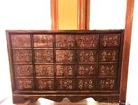 Front view of full apothecary cabinet with all drawers visible and labeled in Chinese characters. Dark wood and metal ring pulls.