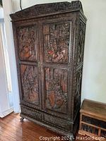 Overall front view of the armoire showing four carved door panels and bracket feet