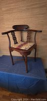 Full view of carved mahogany corner chair showing overall shape and wood finish.