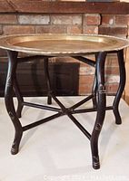 Coffee table with brass tray top and bamboo-style legs in front of brick background