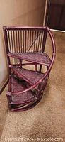 Diagonal view showing the front and curved outer edge with rattan railing of the three-tier rattan staircase plant stand.