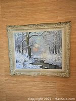 Front view of the oil painting showing winter forest stream scene in ornate gilded frame