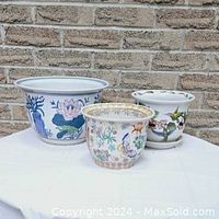 Photo showing three porcelain pots of varying sizes on a white cloth against a stone brick wall background, illustrating the lot contents and size.