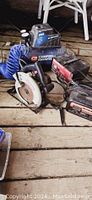 Photo showing the Campbell Hausfeld air compressor, blue coil hose, Craftsman circular saw, and MotoMaster battery charger grouped together on a wooden floor.