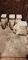 Four white porcelain elephants with square tops, detailed ornamental and floral carvings visible, shown on floor and carpeted surfaces.