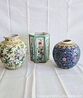 Front view of three Chinese porcelain vases showing floral designs and unique shapes.