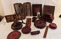 Full view of vintage Asian decor assortment on white cloth background including folding screen, wall plaques, boxes, bowls, incense holder, and vase stands.