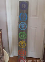 Full view of wooden wall decoration showing all chakra symbols in vertical arrangement and visible paint chipping and wear.