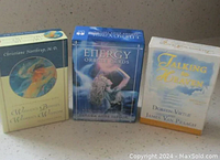 Three oracle card decks in their boxes: Women's Bodies, Women's Wisdom by Dr Christiane Northrup; Energy Oracle Cards by Sandra Anne Taylor; Talking to Heaven Oracle Cards by James Van Praagh and Doreen Virtue.