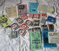 Photo of multiple playing card decks and instructional pamphlets arranged on white fabric background.