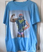 Full view of blue T-shirt with Macho Man Randy Savage graphic showing muscular wrestler in colorful attire.