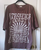 Full front view of the dark brown Pacific Coast t-shirt with large white graphic and text.