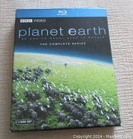 Front cover of the Planet Earth 4-disc DVD set showing elephants and birds on a green field under a blue sky.