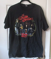 Full view of black T-shirt with front print showing The Doobie Brothers band and tour 2023 text.