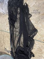 Black collapsible golf practice net laid out on plywood subfloor