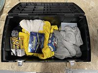 Top view inside black plastic container showing two boxes of Titleist NXT Tour golf balls, poker chips, playing cards, yellow and gray cloth items.
