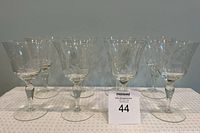 Eight clear crystal wine glasses displayed in two rows, showing the etched floral pattern and faceted stems.