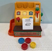 Full front view of the Fisher Price kids cash register toy with colorful buttons and 4 plastic coins placed in front.
