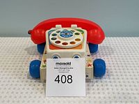 Front angled view showing the rotary dial and red handset on the vintage Fisher Price Chatter Telephone toy.