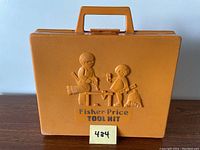 Front view of brown Fisher Price Tool Kit plastic carrying case with handle and embossed children at work design.
