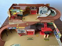 Top view of Hot Wheels Service Center playset with ramps, red garage doors, and building facades including fire station and gas station.