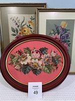 Lot of three framed vintage needlepoint pictures showing floral designs; two rectangular and one oval frame.
