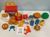 Main photo showing entire lot with Happy Meal case, fries containers, burger toy, character figures, milk carton, cars, and other collectible McDonald's toys.
