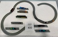 Overview photo showing arranged grey plastic track in two separate loops and multiple train cars set on and alongside track.