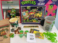 Full lot photo showing all TMNT collectibles laid out including mirror, giant puzzle box, mugs, rings, ruler, and City Sewer Chain Game items