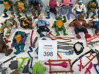 Full view of many TMNT figures of turtles and villains laid out showing damage and many weapons and accessories