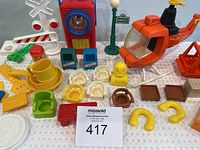 Close-up image showing various vintage Fisher Price toys including a helicopter, light post, traffic signals, and small seats