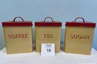 Front view of the three vintage canisters labeled COFFEE, TEA, and SUGAR with red lids and cream-colored bodies