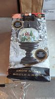Photo of the boxed FAO Schwarz decorated snow globe showing the product image and descriptions on box including automated continuous snowfall and 4 hour timer features.