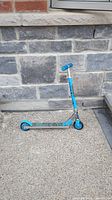 Side view of a blue and silver kids kick scooter showing the handle grips, wheels, and deck.