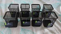 Group photo of 8 black square mesh pen holders placed in two rows.