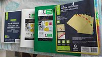 Top view of four binders and one package of index dividers laid out showing brand labels and binder sizes.