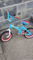 Side view of the whole blue Paw Patrol themed bike showing the frame, wheels, seat and handlebar