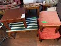 Photo showing two upholstered foot stools stacked, wooden bench with striped cushion below, and small wooden table on top with visible scratches.