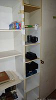 Shelf with multiple shelves containing various boxed items and black mugs