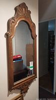 Full view of the tall rectangular wall mirror showing entire carved wooden frame and reflected background.