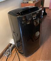 Front and side view of the black DeLonghi Pinguino portable air conditioner showing the overall condition and shape.