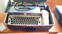 Photo of Smith-Corona Electra 220 electric typewriter inside its hard carrying case with power cord.
