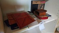 Photo of multiple wallets including a Dockers wallet in box, brown leather and red wallets, and other small pouches plus a multitool set