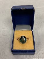 Ring in open blue jewelry box on yellow velvet pad