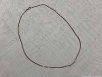 Full length of gold chain laid out on fabric