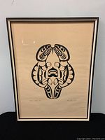 Full view of the framed silkscreen print in beige/cream background with black stylized otter design, showing the entire print and frame.