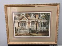 Full view of the framed print showing the house and figures in a soft warm color palette.