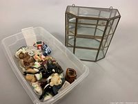 Plastic bin with assorted vintage miniatures, including porcelain and carved stone figurines, small items in various colors and shapes.