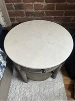 Top view of one nightstand showing round white marble top with subtle veining